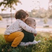 aeltere_schwester_umarmt_kleinen_bruder
